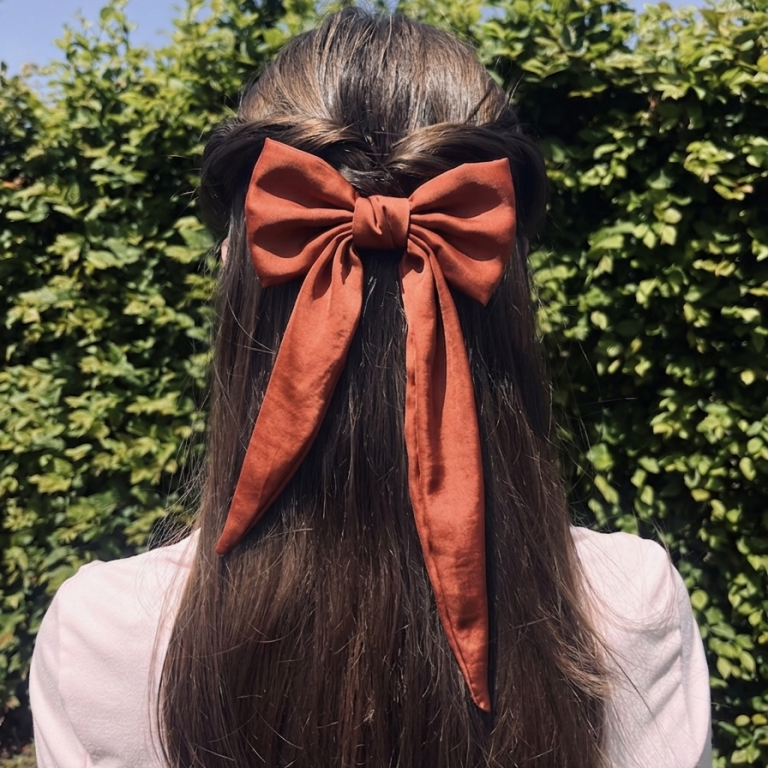 Grande pince nœud en satin terracotta portée dans les cheveux